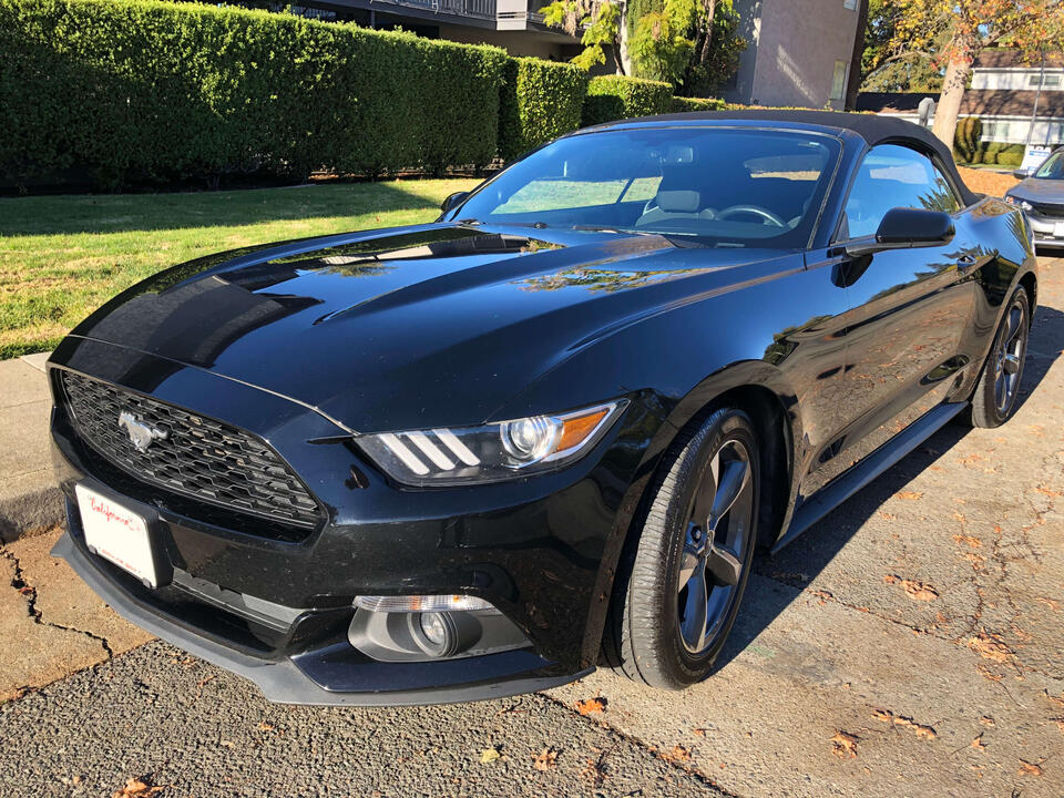 A black 2015 Ford Mustang convertible with its top on